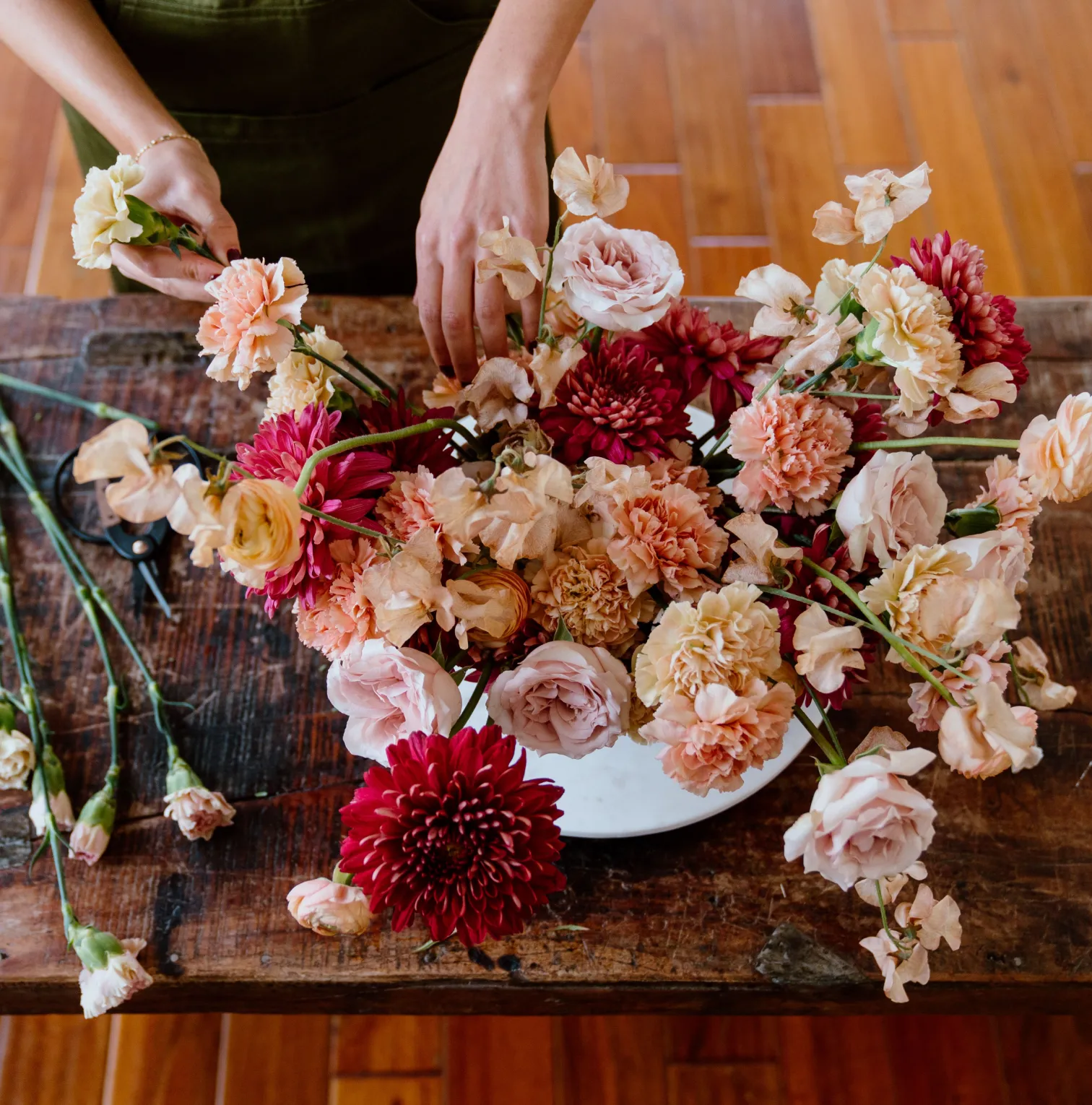 a woman arranging flowers on a wooden table