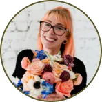 a woman with glasses holding a bouquet of flowers