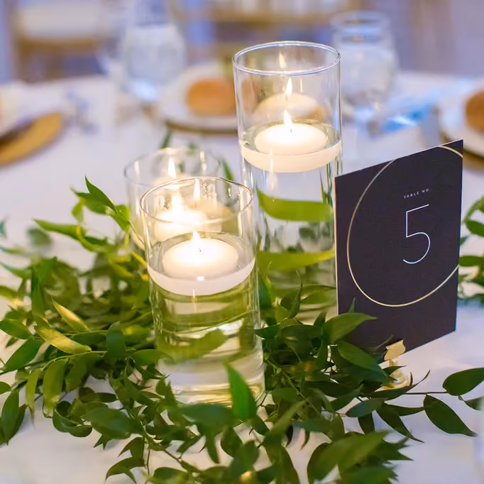 Enhance your wedding decor with loose, lush greenery surrounding romantic candlelight.