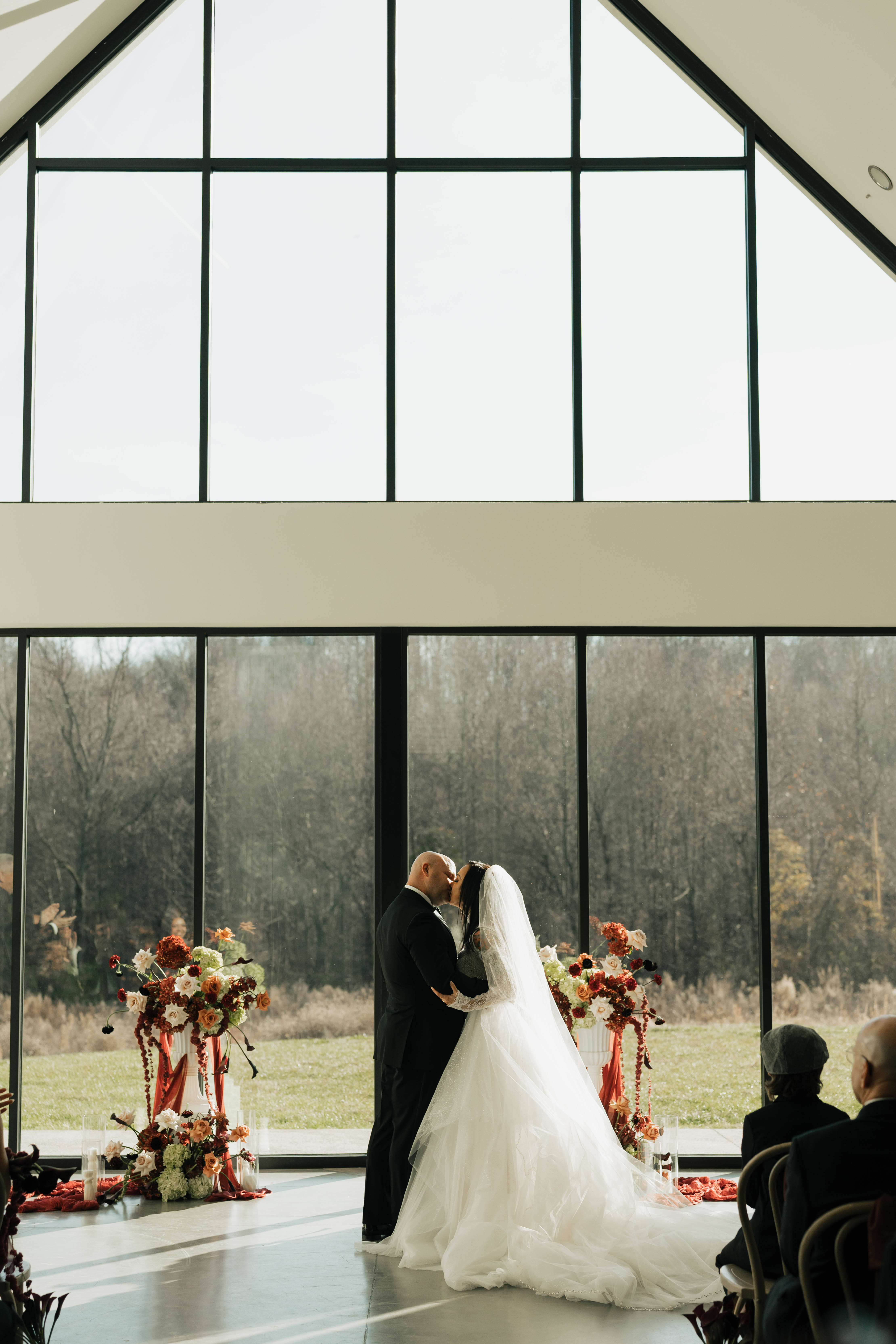 Modern minimalist venue with dramatic burgundy floral arrangements complementing black and white architecture
