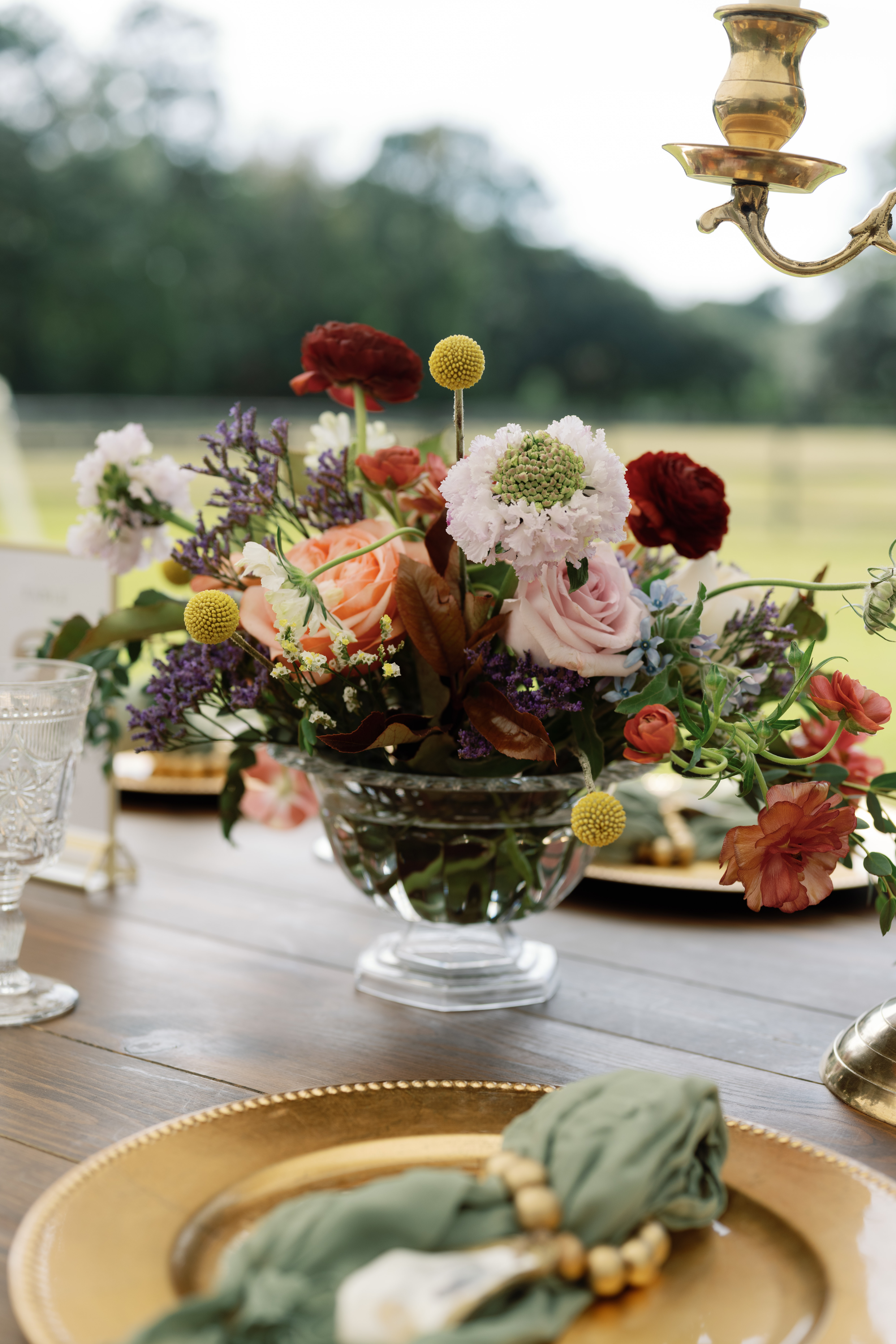 Reception table centerpiece featuring seasonal flowers and lush greenery by Poppy Flowers