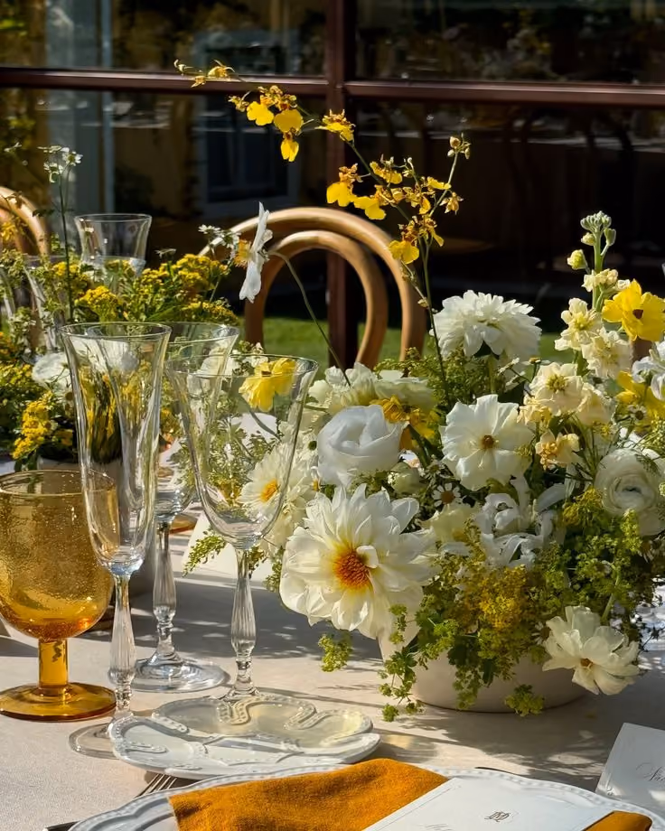 This may contain: the table is set with glasses and flowers in vases, plates and napkins