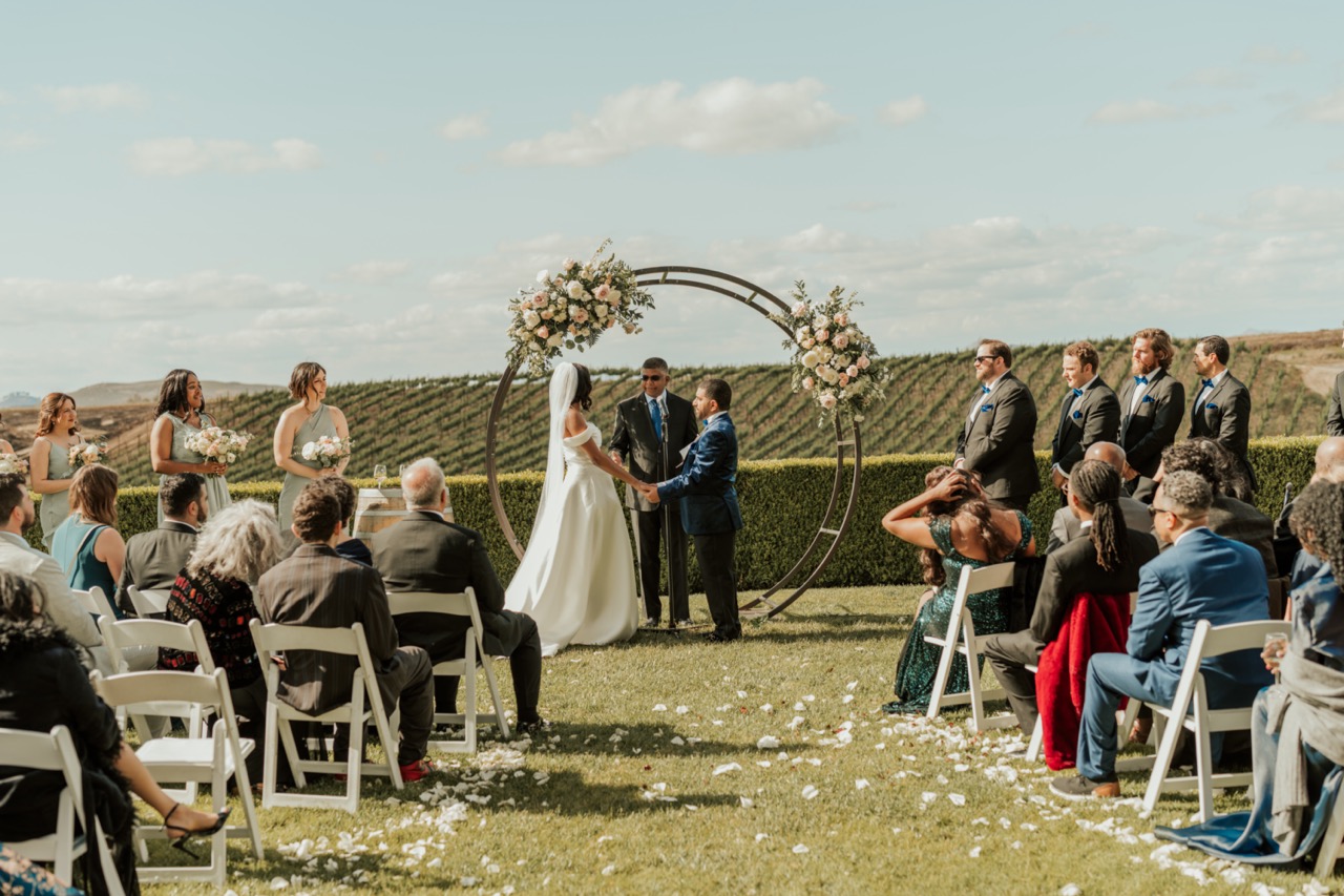 Outdoor wedding ceremony at Callaway Vineyard & Winery with a circular arch decorated with blush and white flower clusters
