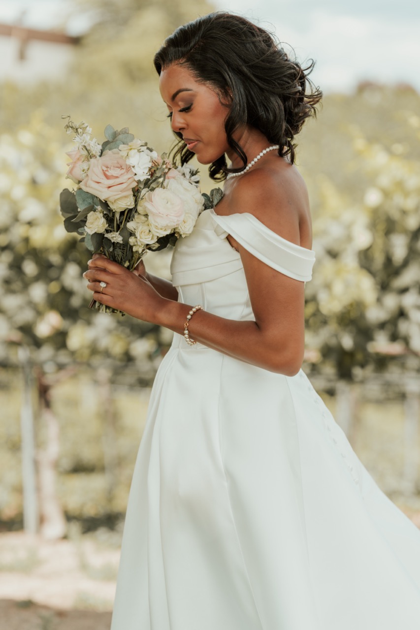 Bride smelling her blush and white rose bridal bouquet among the grapevines at Callaway Vineyard & Winery