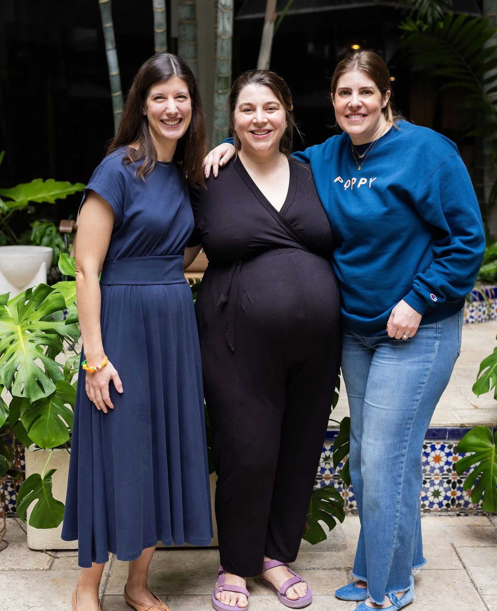 Anne Rodriguez, Cameron Hardesty and Jenny Rajendra standing arm in arm among tropical plants