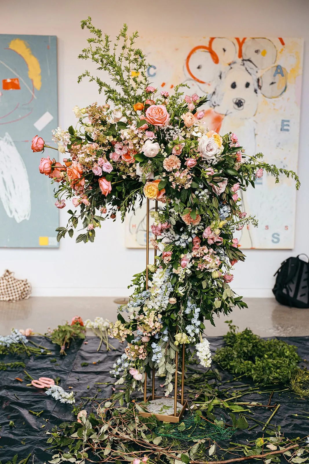 A finished ceremony arch of pink and peach roses, delphinium and trailing greenery