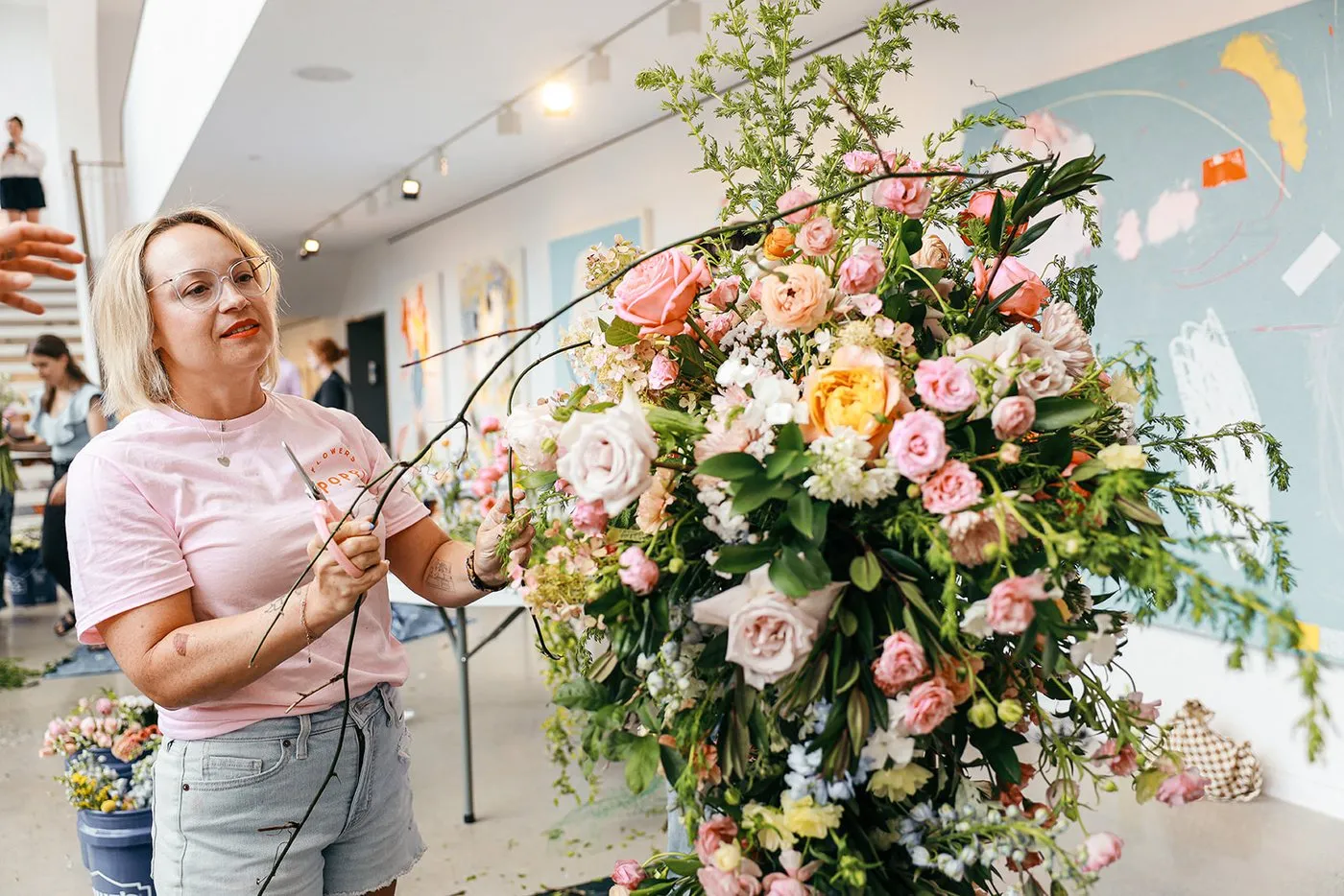 Michelle Edgemont trimming a curving branch for a ceremony arch of pink and peach roses